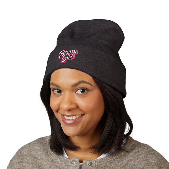 Black beanie with pink 'Bronx Girl' embroidery, worn by smiling woman for NYC streetwear style