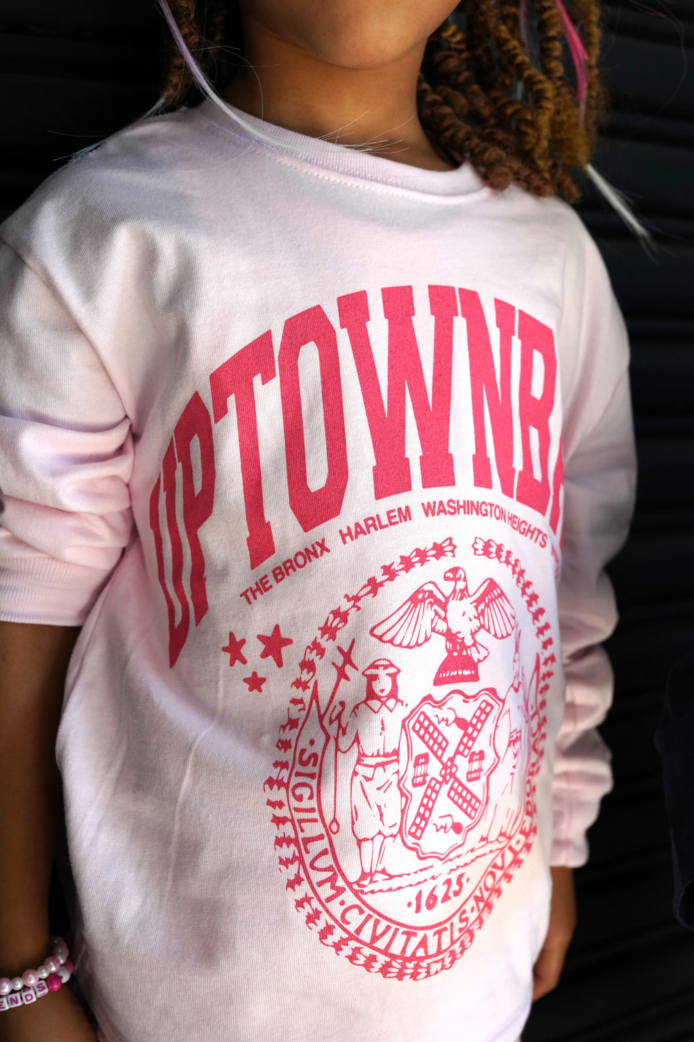 Person wearing a white t-shirt with red 'Uptown' text and graphics.