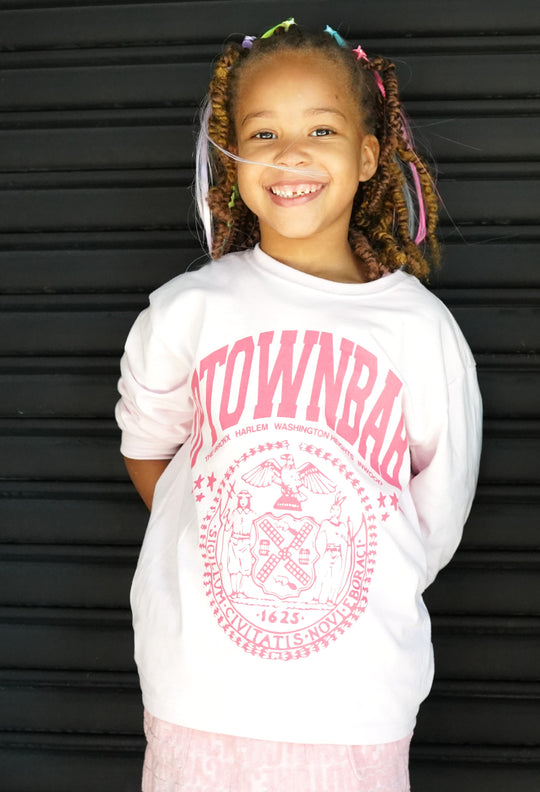 Young girl wearing a white sweatshirt with pink text and graphics against a black background